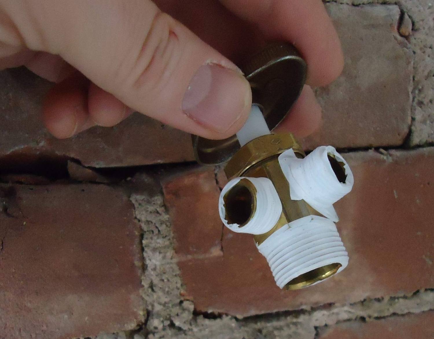 Llave de paso y racor de latón en la pared